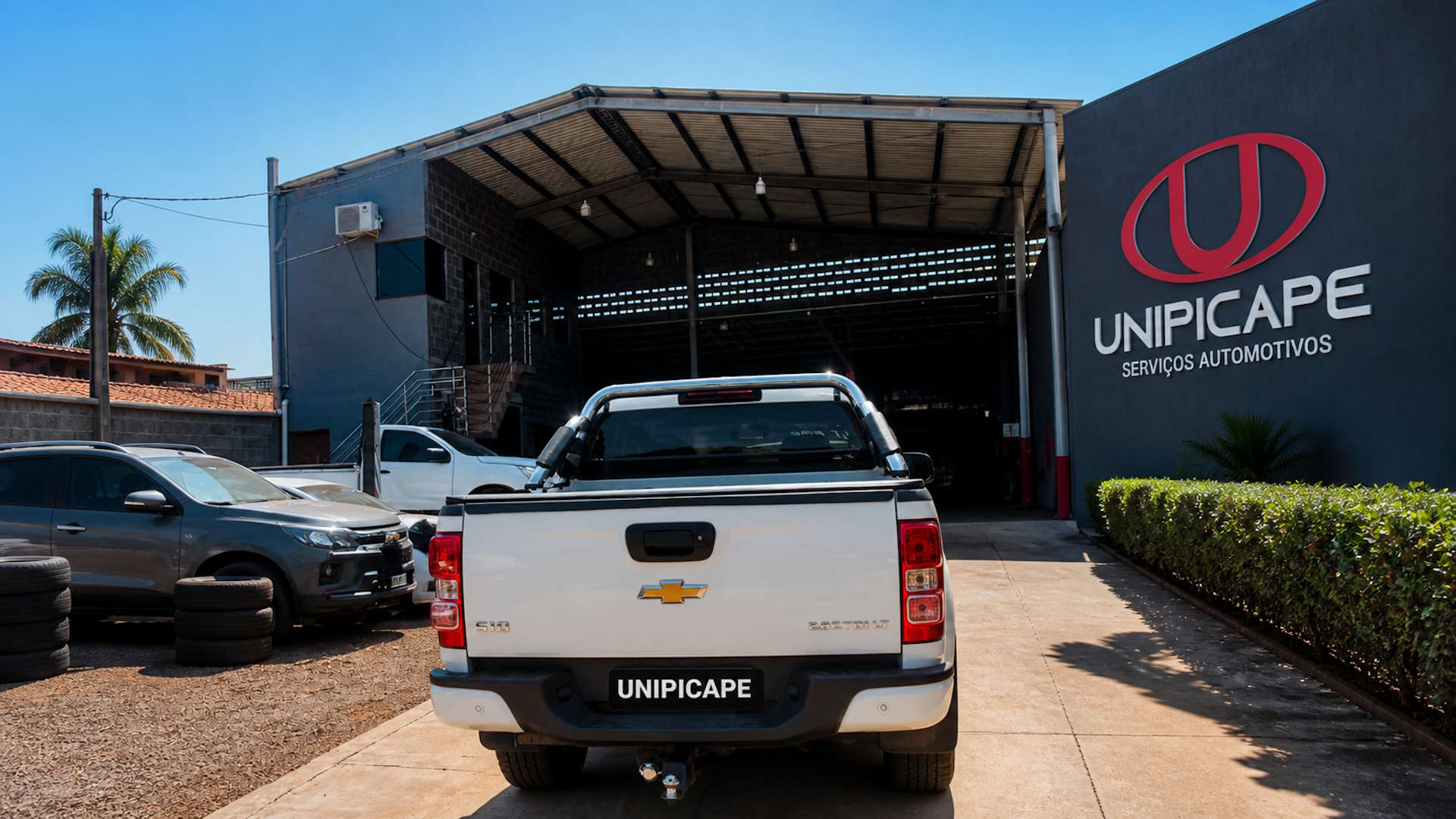 Fachada da oficina UNIPICAPE ao entardecer com picapes estacionadas